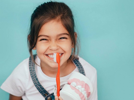 a child smiling while holding a toothbrush in Allen