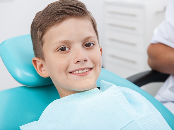 Little boy sitting and smiling in dental chair