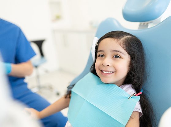 Little girl in dental chair with dentist nearby