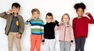 5 diverse children brushing their teeth in a row in front of white background