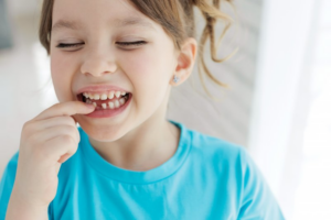 Little girl poking at her wiggly baby tooth