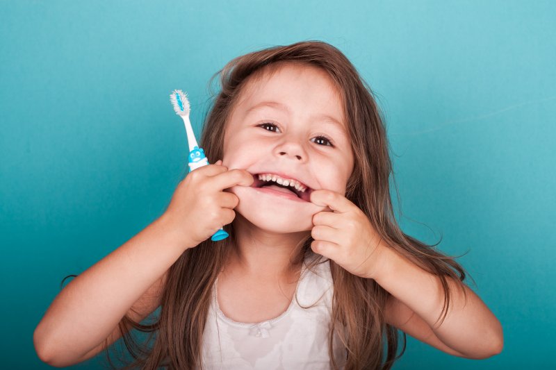 Child with toothbrush makes silly face